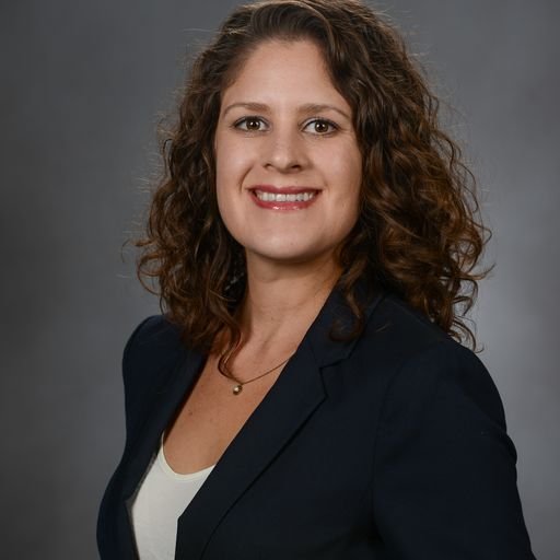 a woman in a business suit smiling for the camera.