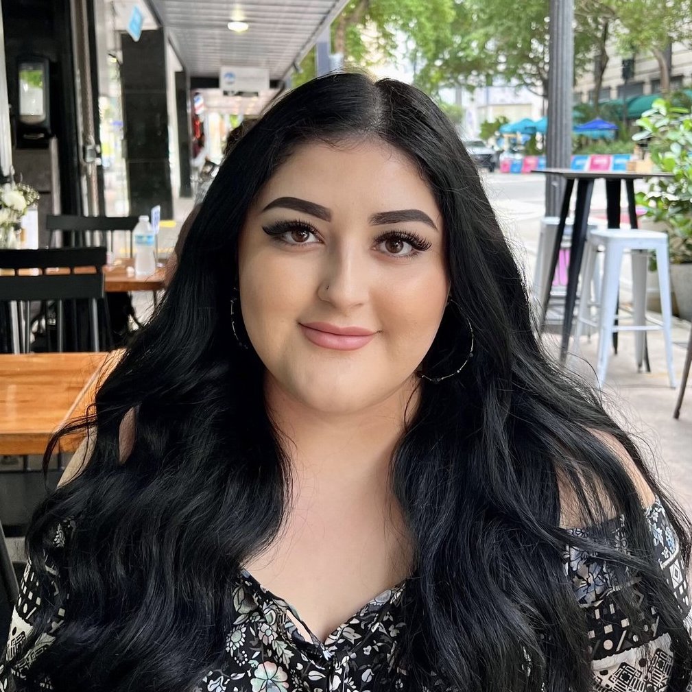 a woman with long black hair sitting in a restaurant.