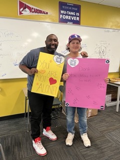 two students holding signs in a classroom.
