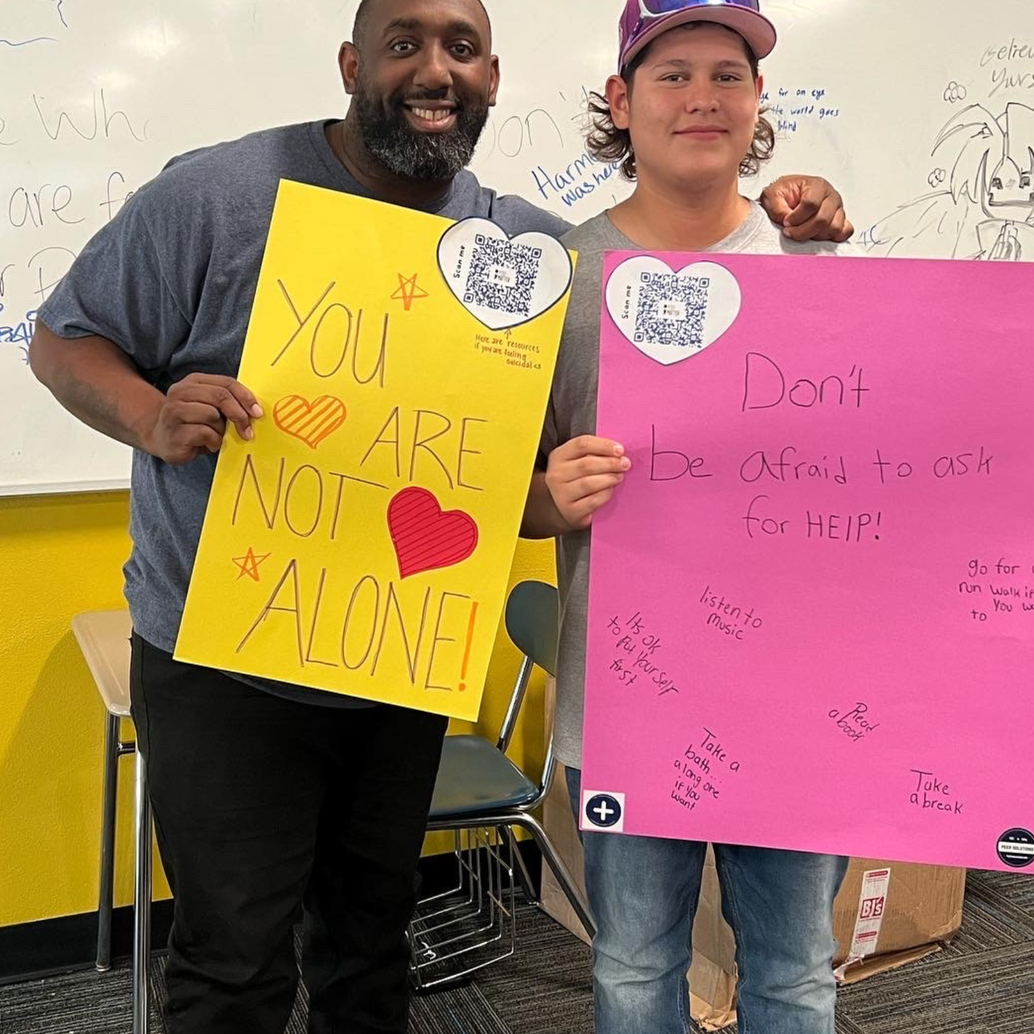two students holding up signs with the words don't be alone.